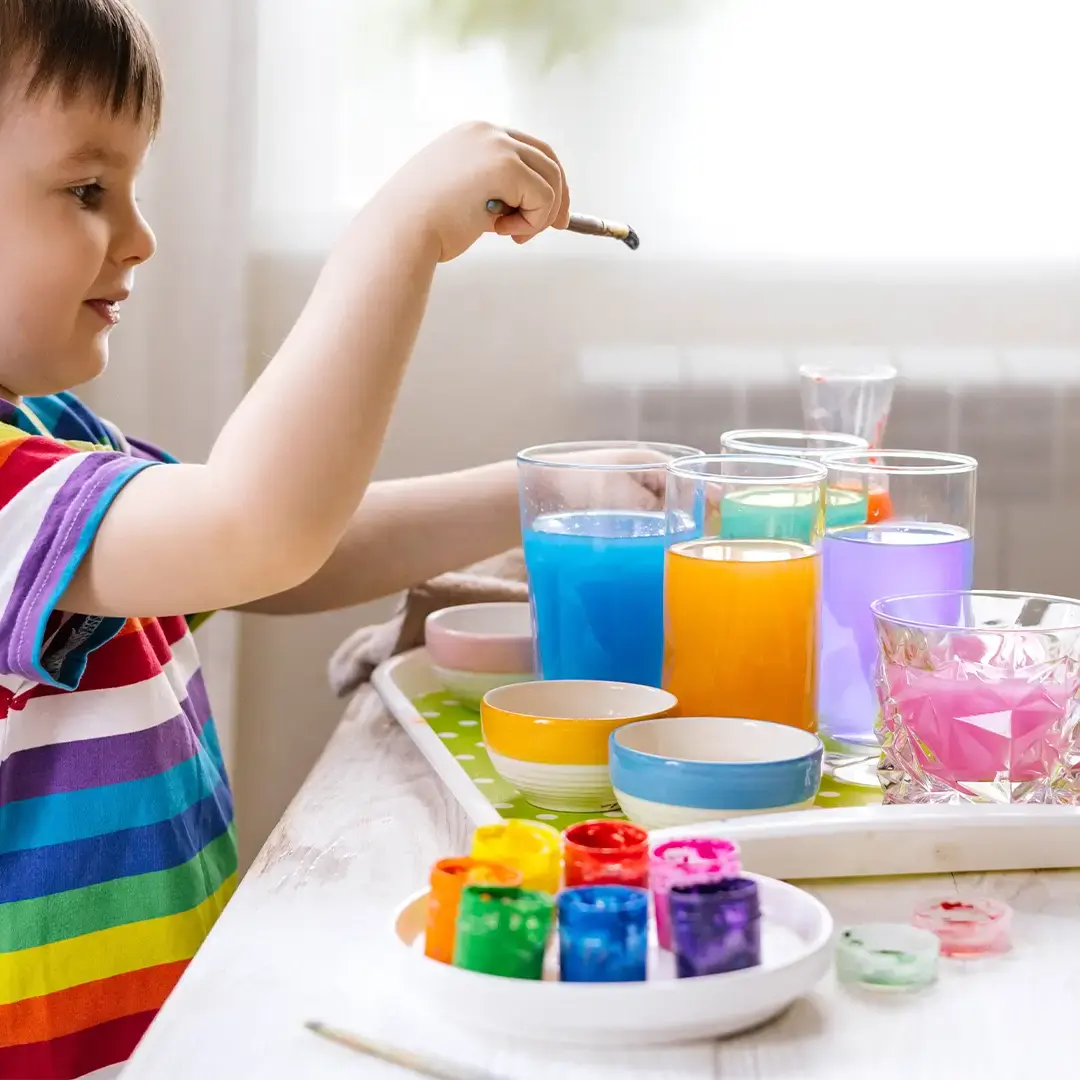 Kind spielt mit Wasser und farben