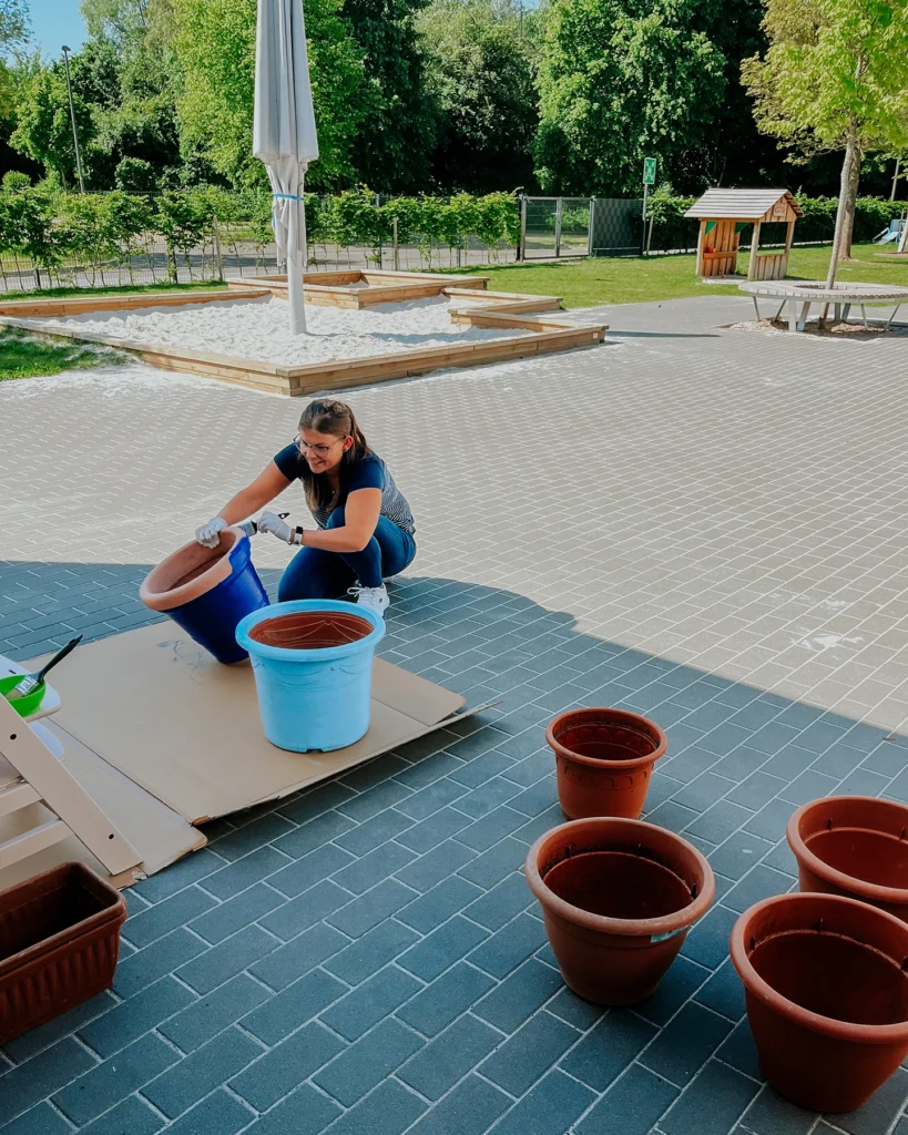 Erzieherin bemalt Blumentopf für Gartenprojekt in der Kita Blausteinsee in Eschweiler