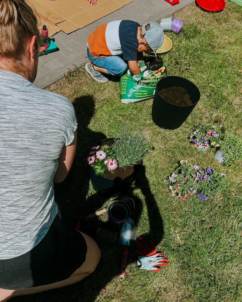 Kind pflanzt Blumen bei Gartenprojekt